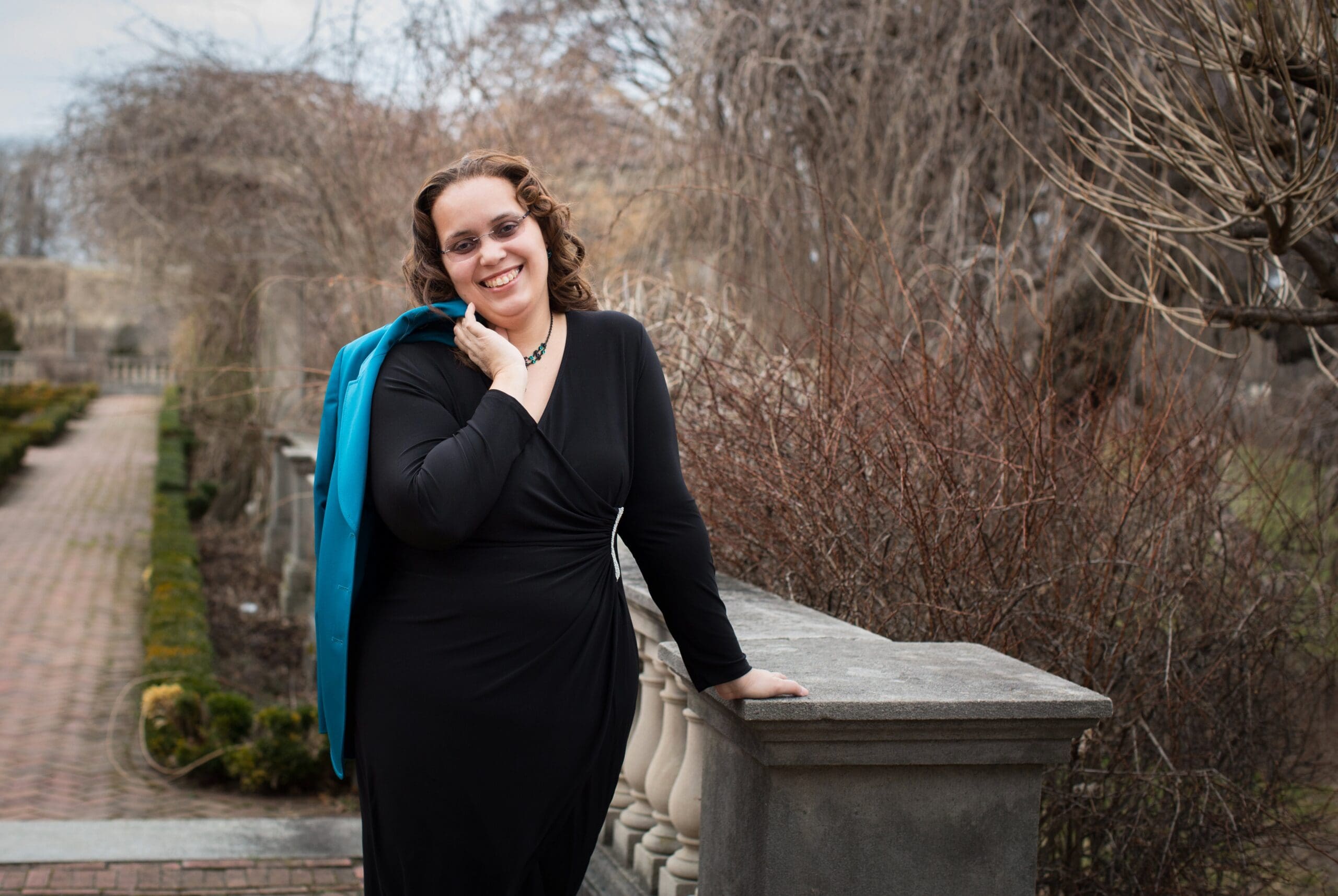 A woman in black dress holding a blue jacket.