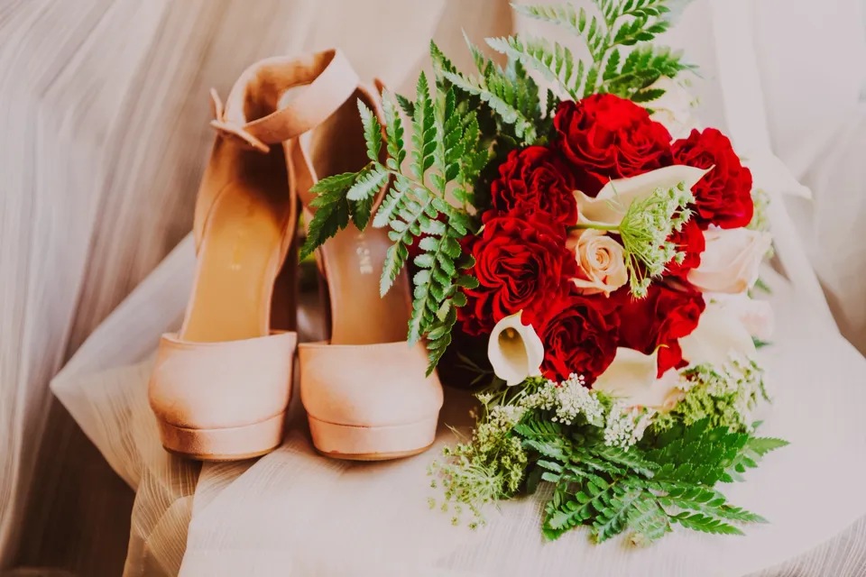 A bouquet of flowers and shoes on the table.