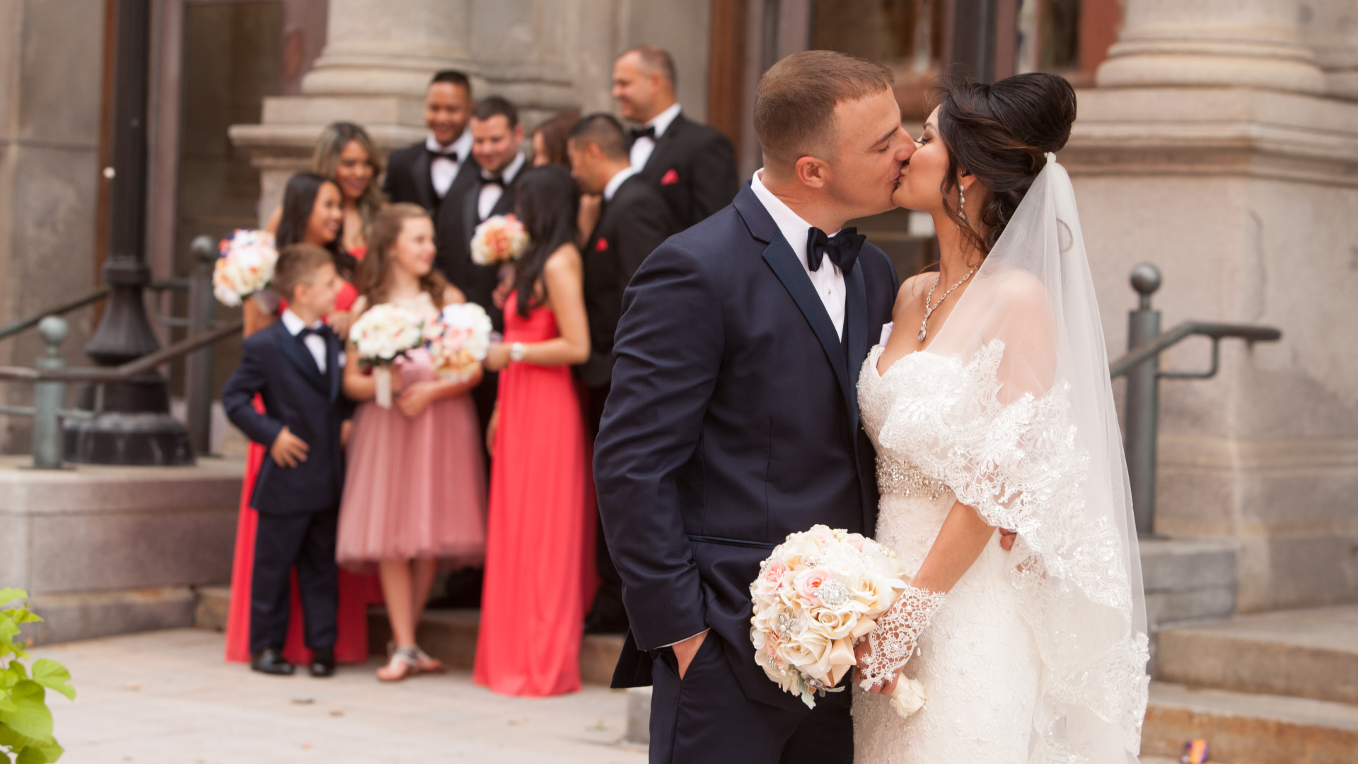 A bride and groom kissing in front of a crowd.